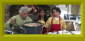 Nina and Rosario wear aprons and watch as a professional chef smells their gumbo.