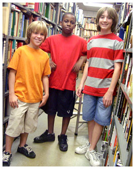 Sam, DJ, and Jay in front of bookshelves in the library.