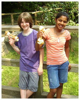 Jay and Harsha standing by a fence holding dog treats.