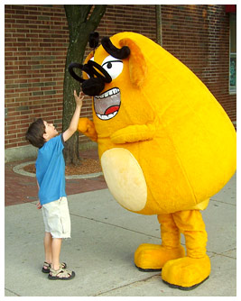 A little boy goes to squeeze the Ruff costume character's nose.