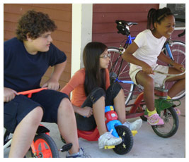 Brian, Talia, and Bethany ride on tricycles.