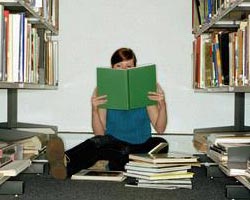 Girl reading book while sitting on floor of library