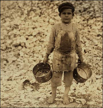 A five-year-old boy next to a pile of oyster shells.