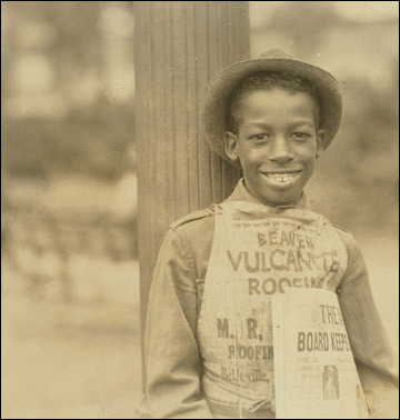 A newspaper boy wearing a hat.